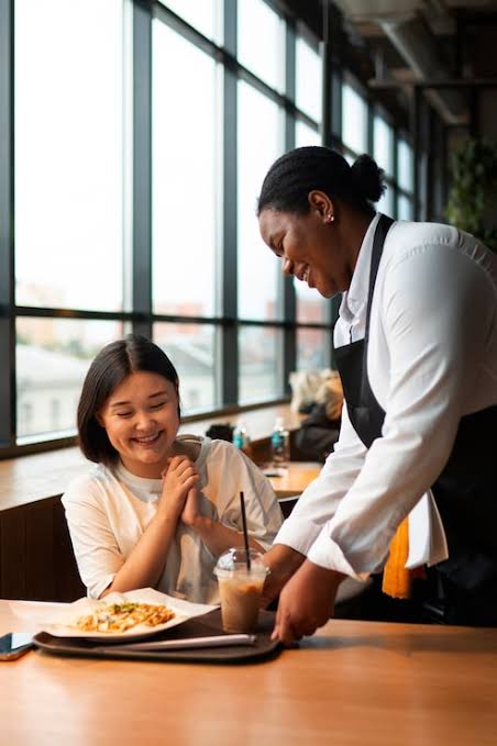 A server warmly attending to a guest at an IHG café table